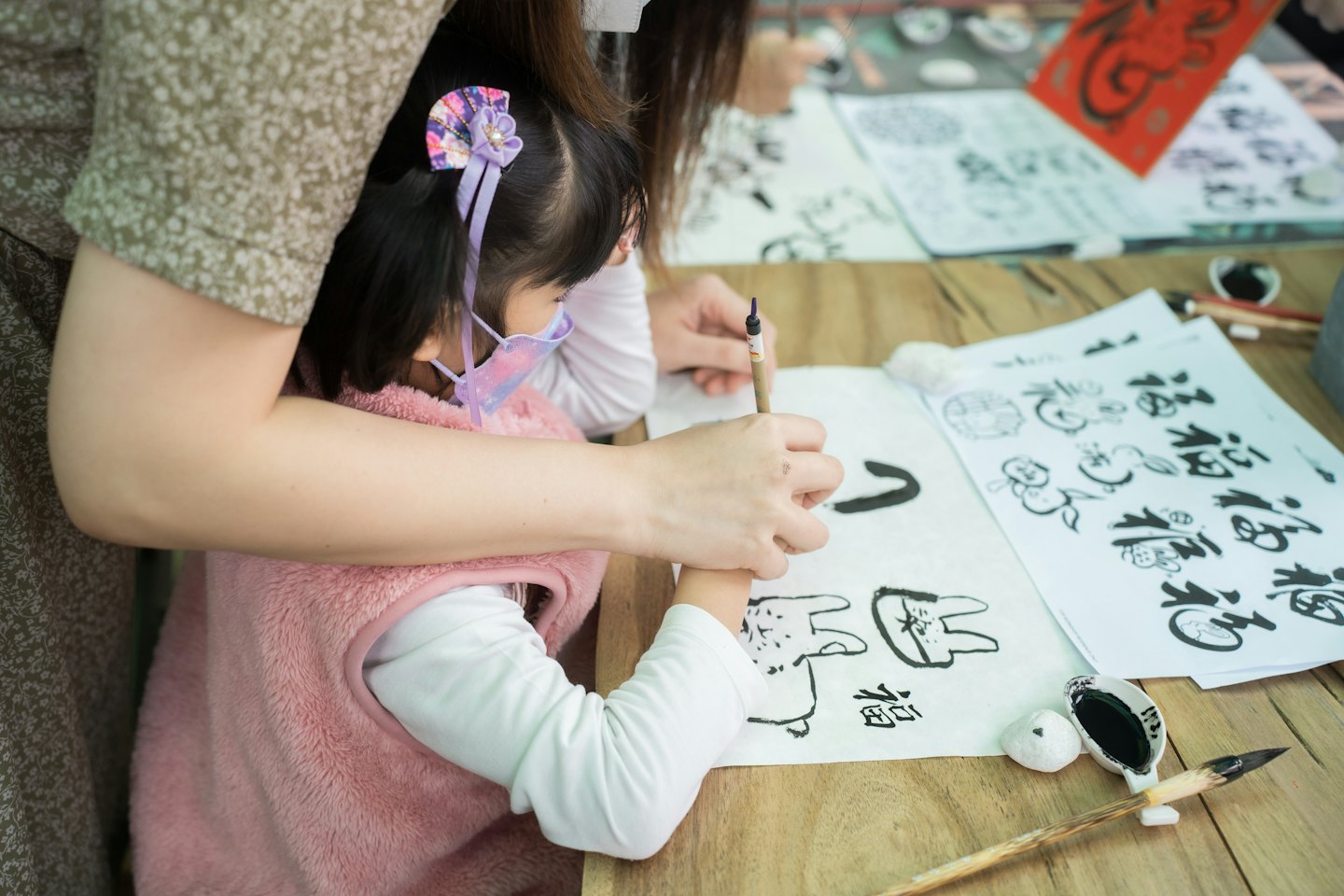 Donna aiuta una bambina a esercitarsi con la calligrafia cinese su carta.
