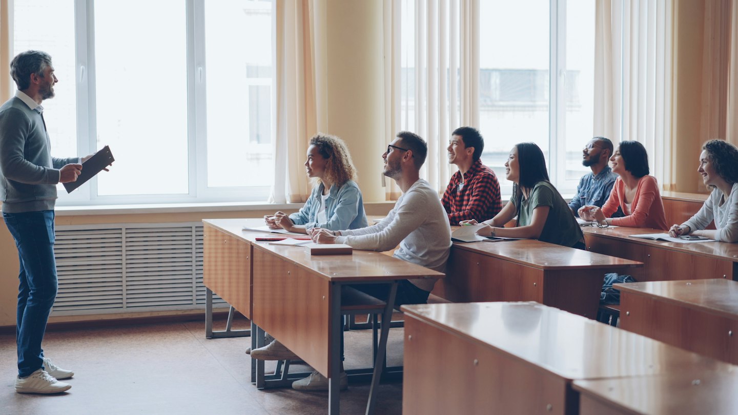 Un istruttore con una lavagna tiene una lezione a studenti universitari attenti in un'aula.